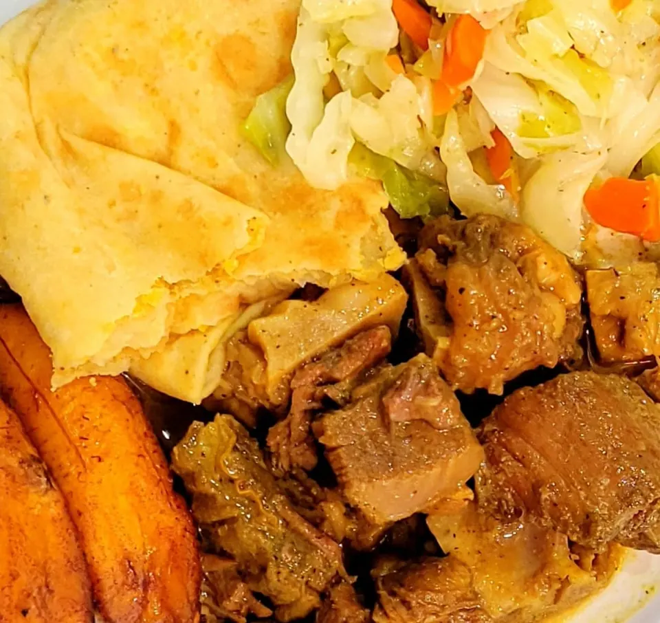 Curry goat with fried plantains, cabbage, and roti